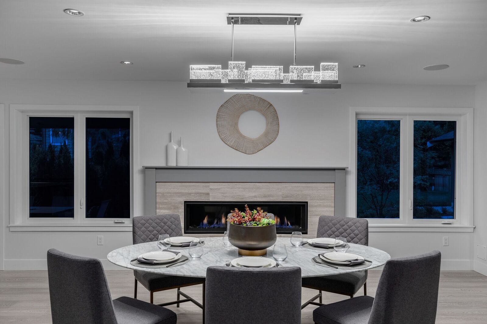 Dining room with round marble table, linear gas fireplace, and crystal chandelier — Seymour Blvd build