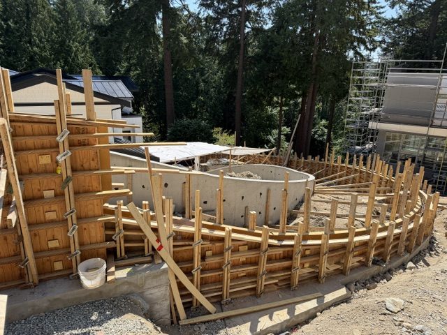 Curved concrete driveway formwork and a stripped circular concrete element on a West Vancouver lot
