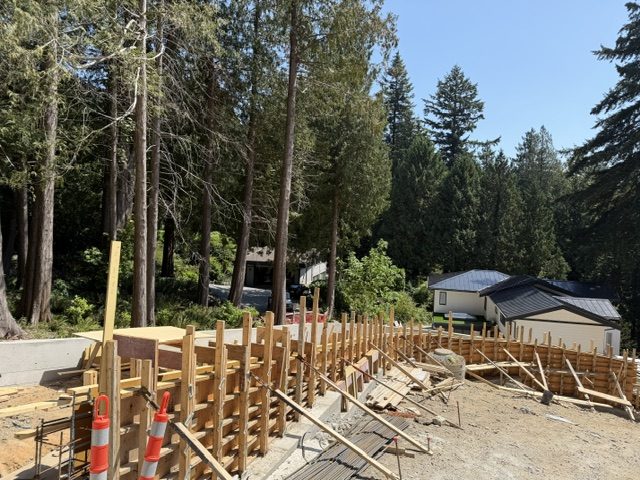 Curved architectural concrete retaining wall formwork on a forested West Vancouver lot