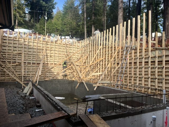 Curved retaining wall in formwork with the pool being formed below, West Vancouver hillside
