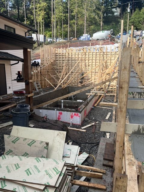 Large braced retaining wall formwork on a steep West Vancouver lot during concrete delivery
