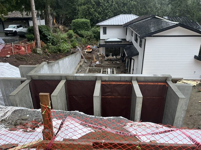 Concrete retaining wall with dimpled waterproofing membrane between buttresses, West Vancouver build