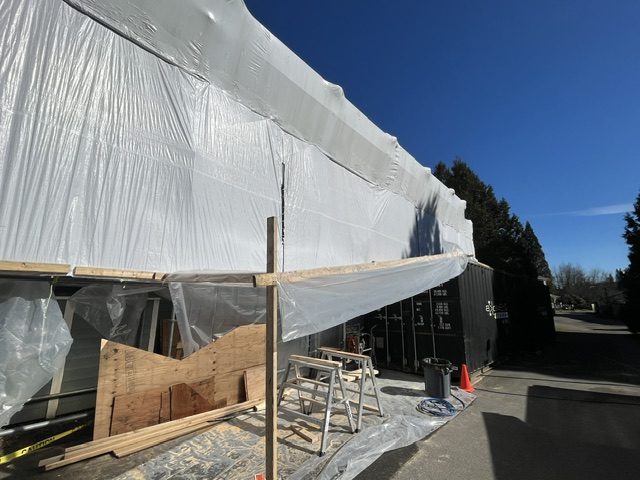 Close-up of shrink-wrap weather containment and scaffolding on the multi-family roof project