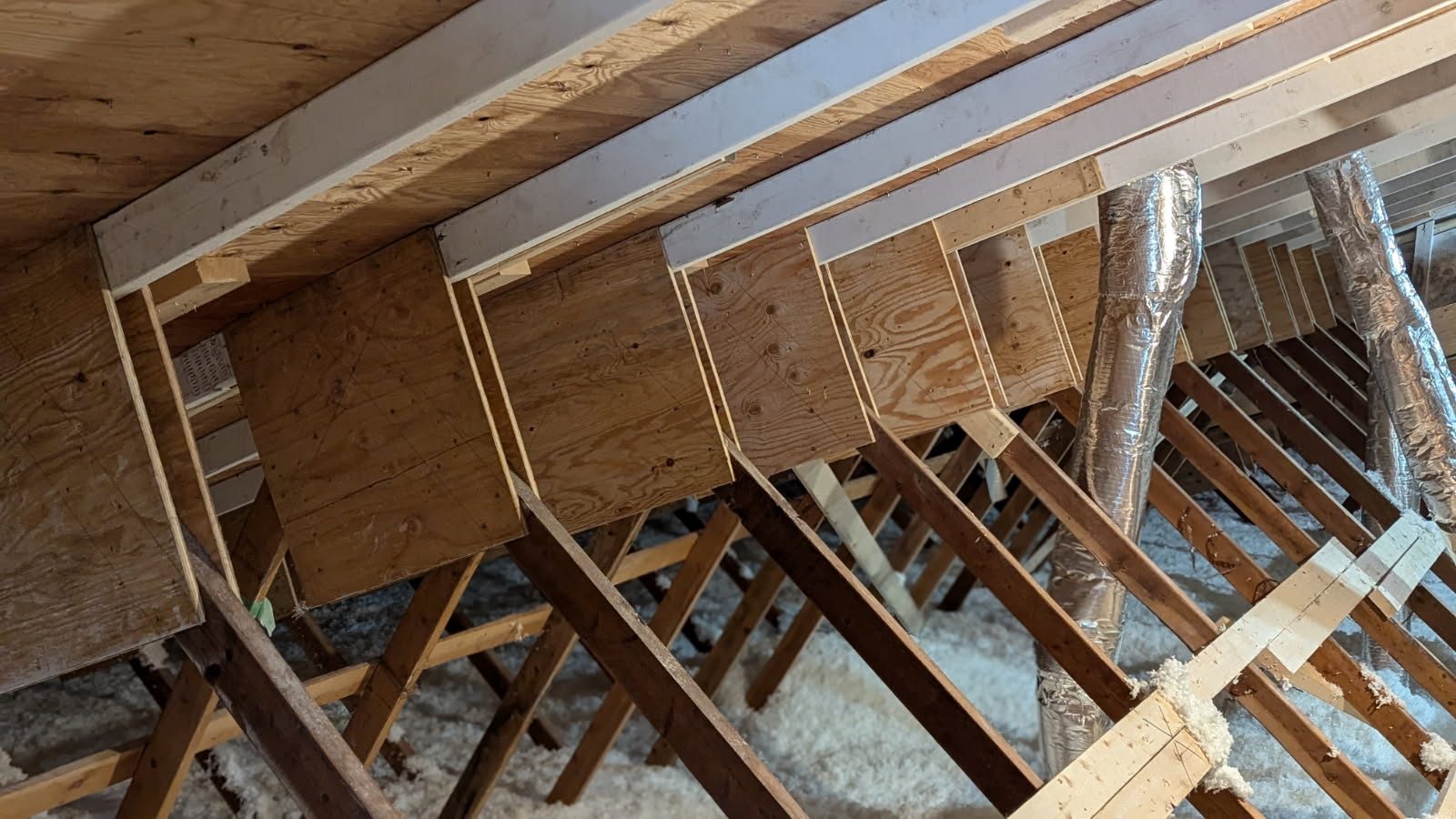 Upgraded roof trusses with new diagonal bracing and ducting in the attic of the North Vancouver multi-family building